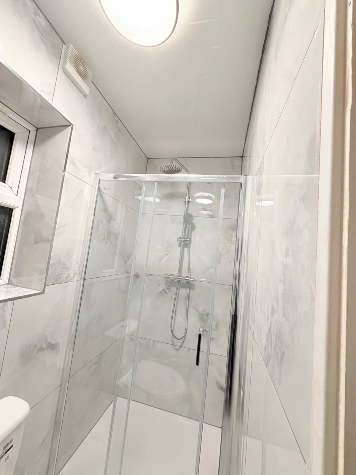 Chrome rainfall shower in a newly tiled bathroom